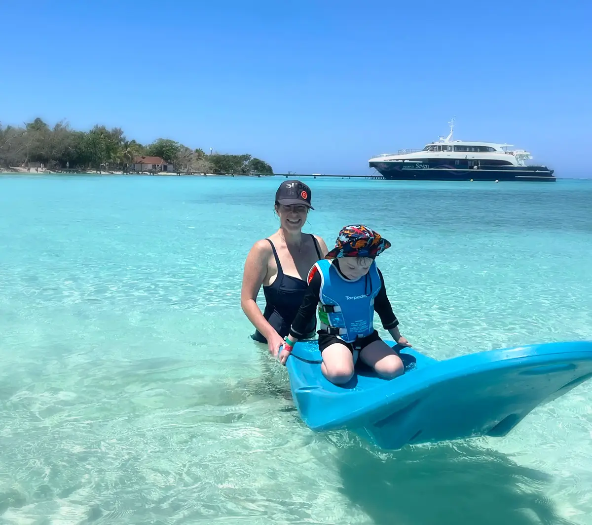 mother and child enjoying crisp ocean swimming, with a cruise boat in the background