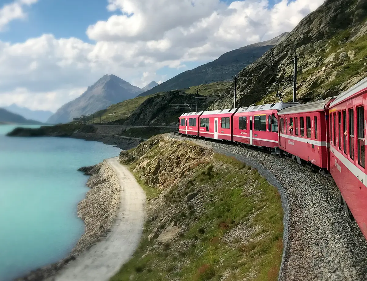 Red train travelling near body of water