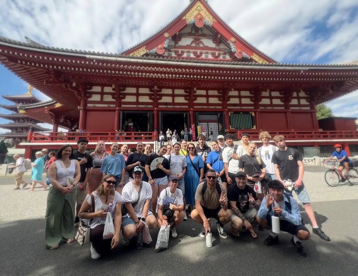 Travel group posing together outside a Japanese building