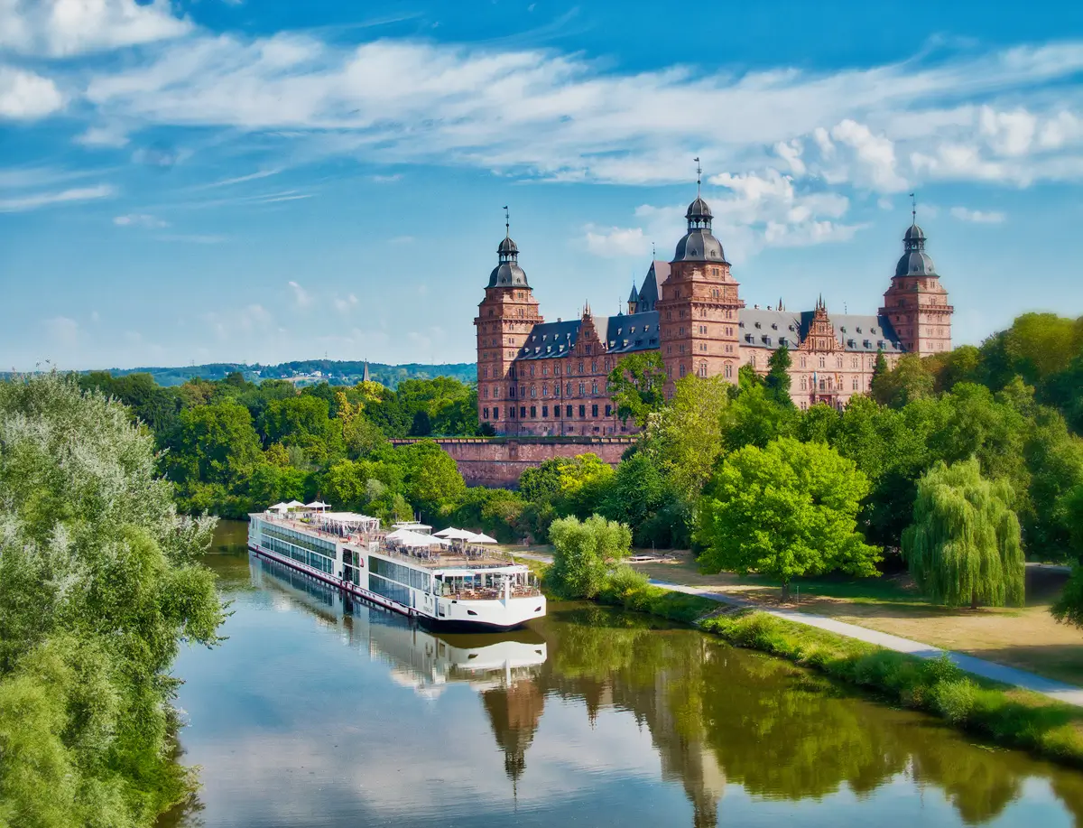 A river cruise ship on a river, with a castle in the background