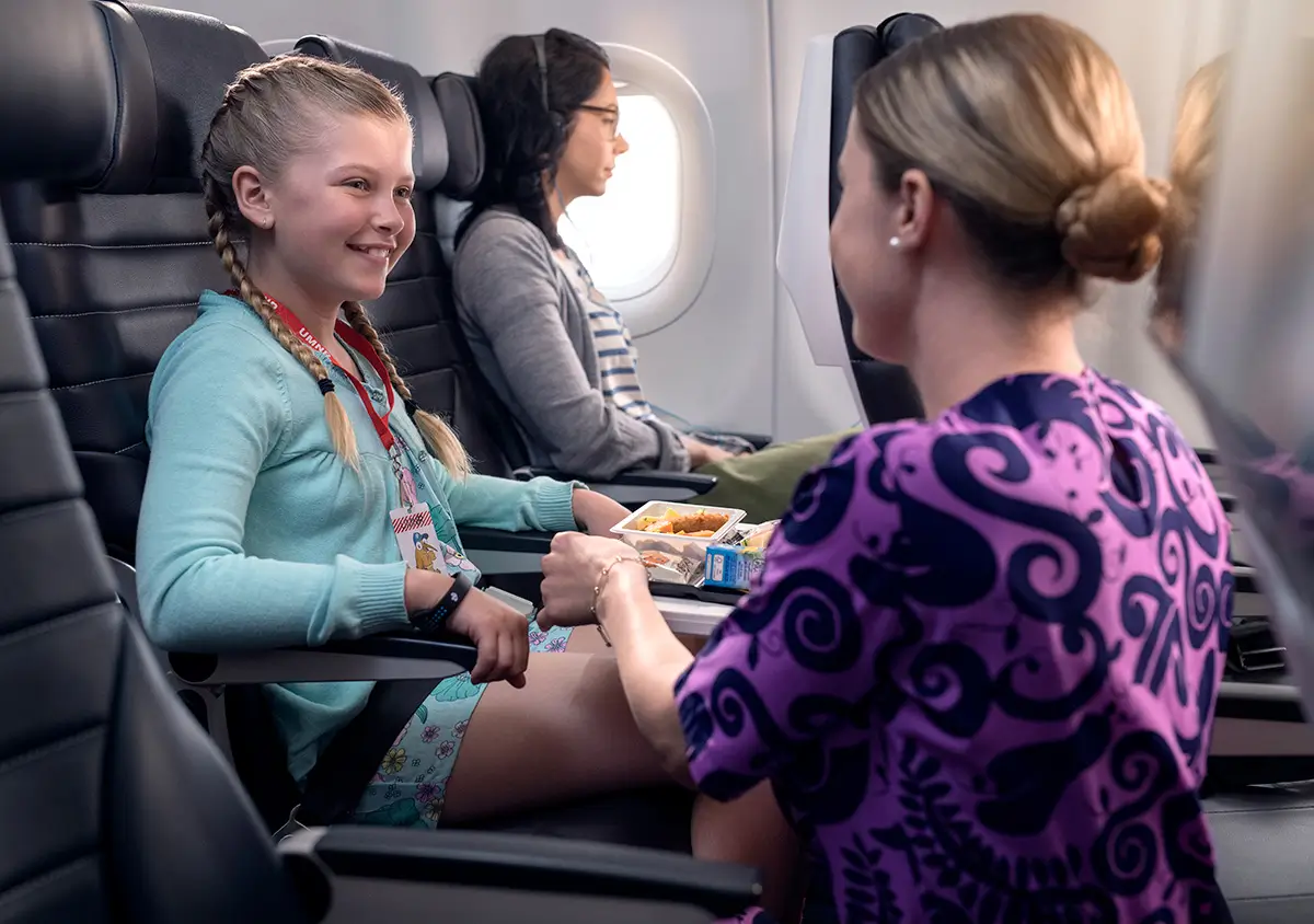 An Air NZ hostess assists a smiling child with food