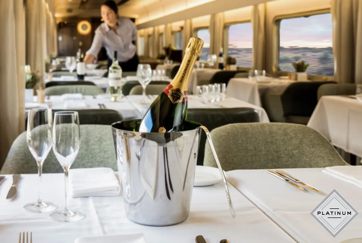 A bottle of champagne sits in an ice bucket on a table in the dining car of an Indian Pacific train.