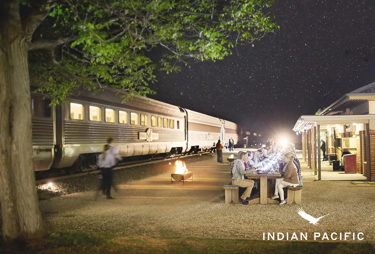 Indian Pacific train with it's passengers dining at a long table outside the train