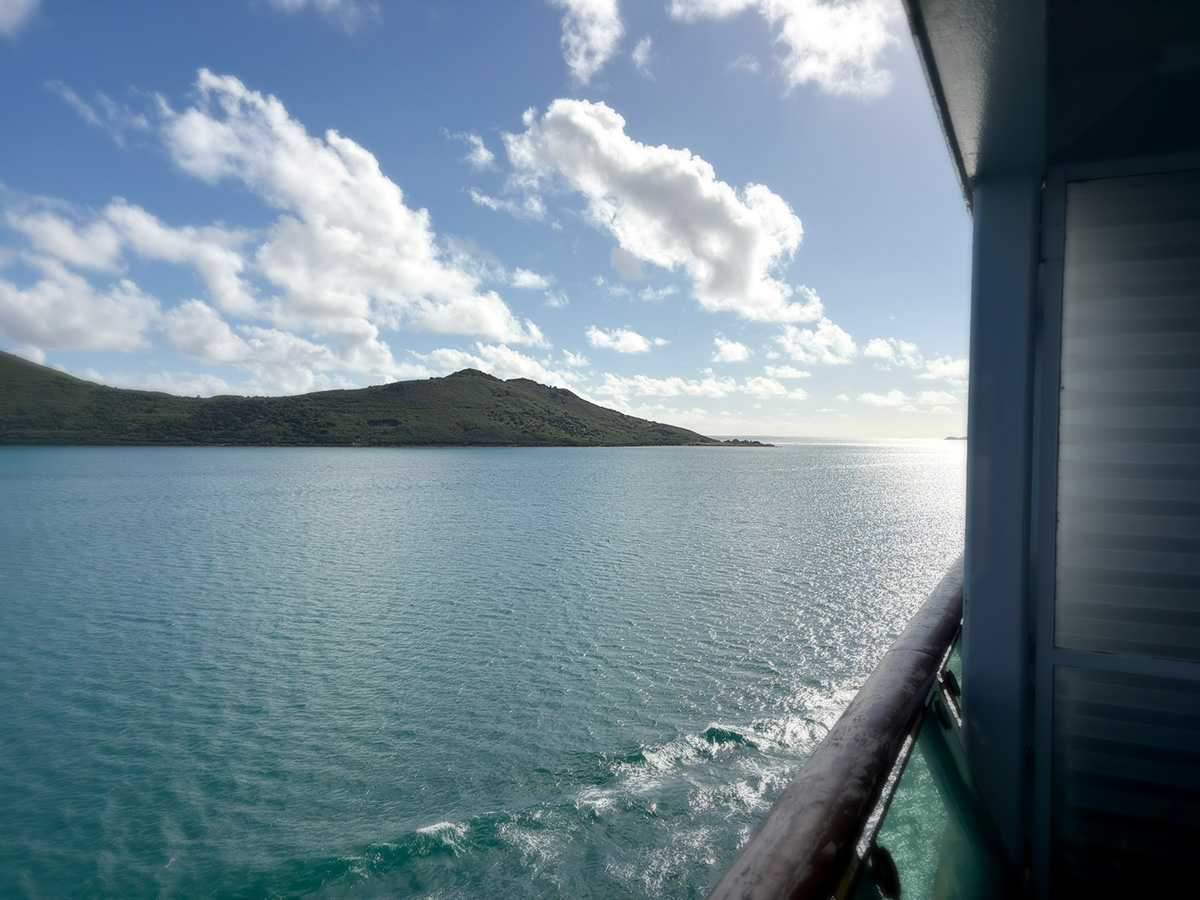 view from the side of a sea vessel, land can be seen in the distance