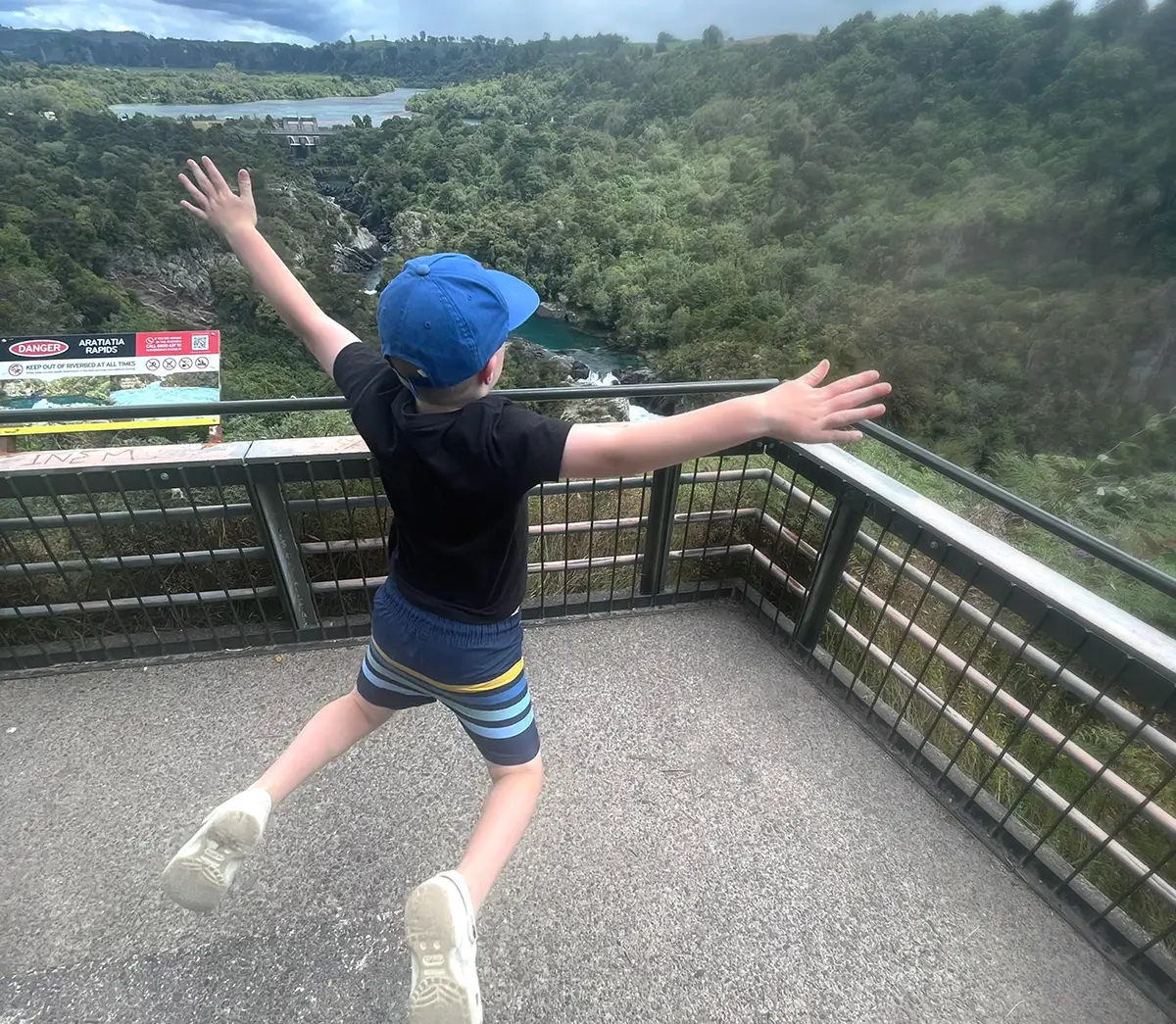 A child jumping in excitement with a view of green forest in the background