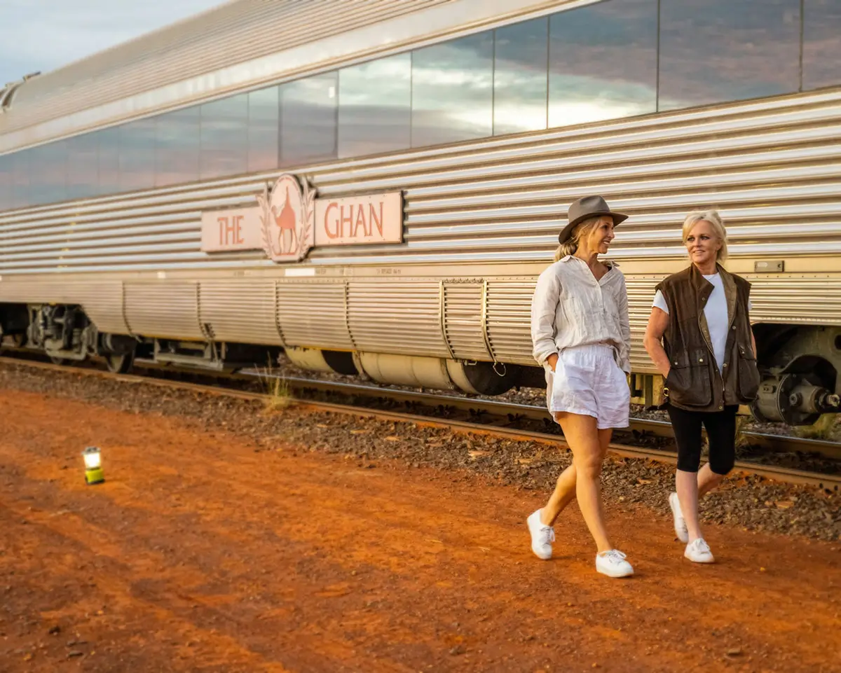 Two people strolling beside 'The Ghan' train