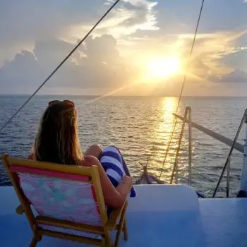 Lydia in the Maldives Lydia relaxing on a boat looking at the sun setting over the water in Maldives