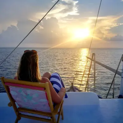 Lydia relaxing on a boat looking at the sun setting over the water in Maldives